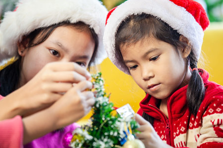 Cute asian child girls decorating christmas tree for celebrate on Christmas festival together with...