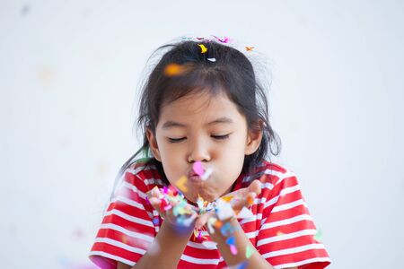 Cute asian child girl with colorful confetti to celebrate in her partyの写真素材