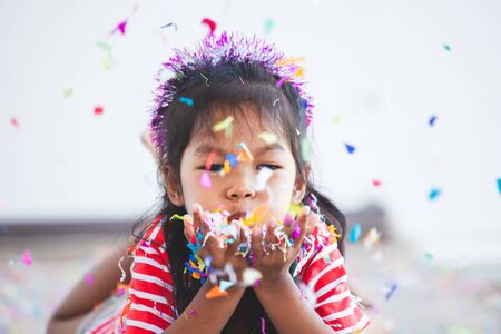 Cute asian child girl with colorful confetti to celebrate in her partyの写真素材