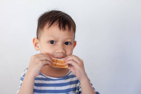 Asian little boy eating bread before go to schoolの写真素材