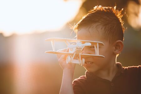 Cute asian child boy playing with toy wooden airplane in the park at sunset time with funの写真素材