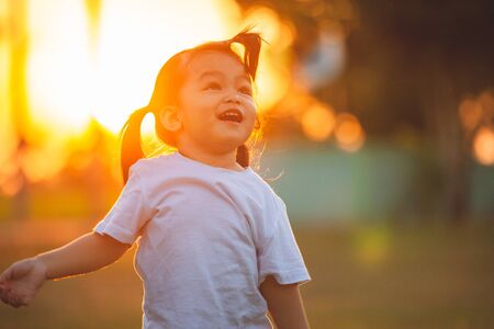 Cute asian little child girl walking and playing in the park at sunset time with fun and happinessの写真素材