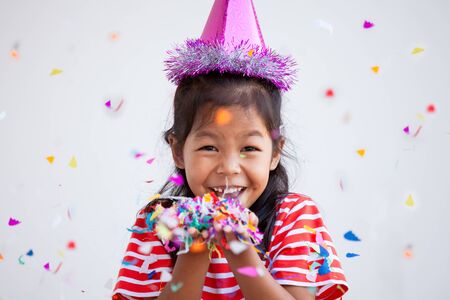Cute asian child girl with colorful confetti to celebrate in her partyの写真素材