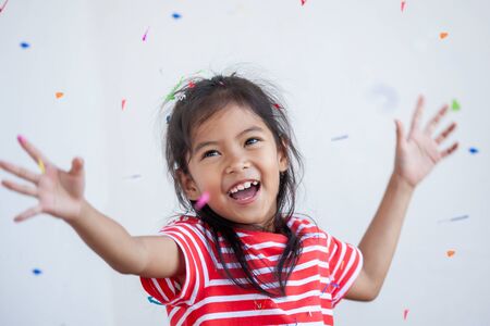Cute asian child girl with colorful confetti to celebrate in her partyの写真素材