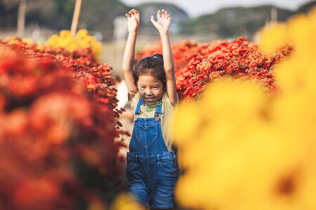 Cute asian child girl having fun to run and play in the flower gardenの写真素材