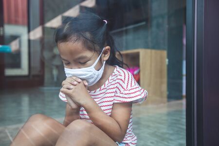 Asian child girl wearing protection mask praying for a new day freedom to coronavirus Covid-19 and stay at home quarantine from the coronavirus Covid-19 and air pollution pm2.5.の写真素材