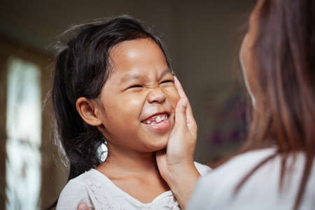 Asian child girl is smiling when mother touching her face. Mother is helping her child girl get ready for school.の写真素材
