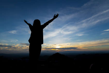 Silhouette of asian woman raise her arms looking at the mountain and enjoy with beautiful nature with freshness and happinessの写真素材