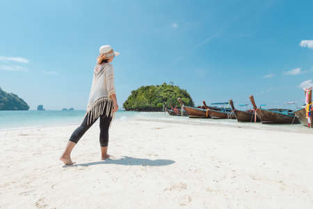 Asian woman walking on the beach and enjoying with beautiful nature in her vacation. Summer holidays and travel concept. Travelling in Thailand.の写真素材