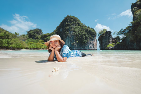 Asian woman lying down on the beach and enjoying with beautiful nature in her vacation. Summer holidays and travel concept. Travelling in Thailand.の写真素材