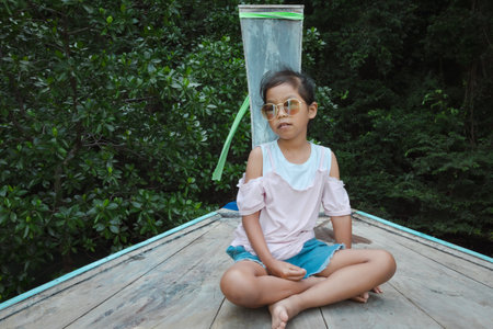 Cute asian child girl sitting on the head of wooden longtail boat travel on the sea go to the amazing island and lagoon and enjoying with beautiful nature in her vacation with family.の写真素材