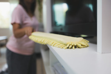 Woman cleaning and wiping the cabinet with microfiber cloth duster in the living room. Woman doing chores at home. Housekeeping concept.の写真素材