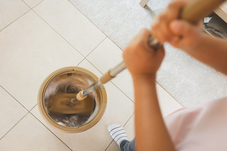 Woman holding a mop spinning in the bucket to cleaning and mopping the floor in the living room....