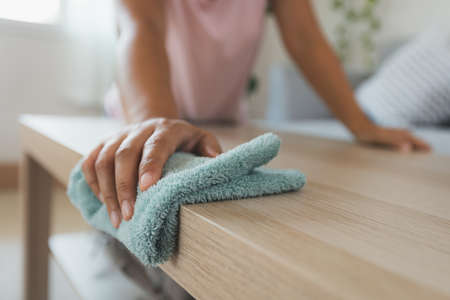 Woman cleaning and wiping the table with microfiber cloth in the living room. Woman doing chores at home. Housekeeping concept.の写真素材