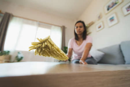 Woman cleaning and wiping the table with microfiber cloth duster in the living room. Woman doing chores at home. Housekeeping concept.の写真素材