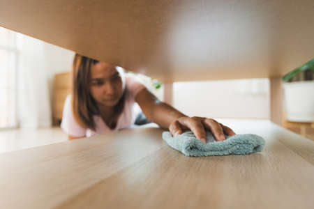 Woman cleaning and wiping the table with microfiber cloth in the living room. Woman doing chores at home. Housekeeping concept.の写真素材