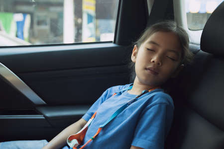 Asian child girl is sleeping in the car while traveling to school. Childhood and family lifestyles in car concept.の写真素材