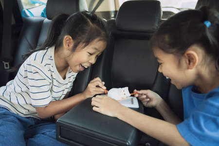 Two asian child girls eating dessert together while traveling in the car. Childhood and family lifestyles in car concept.の写真素材