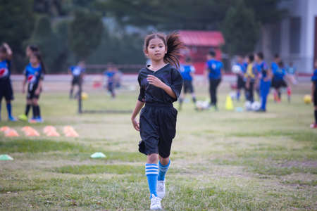 Asian child girl running and exercise warm up before play soccer in the field. Kid sport recreation concept.の写真素材