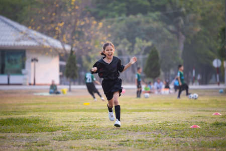 Asian child girl making funny face and running with happiness in the soccer field. Child is happy after win in game. Kid sport recreation concept.の写真素材