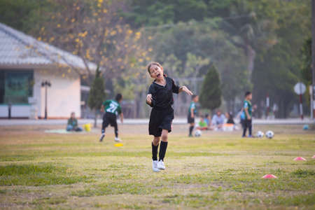Asian child girl making funny face and running with happiness in the soccer field. Child is happy after win in game. Kid sport recreation concept.の写真素材