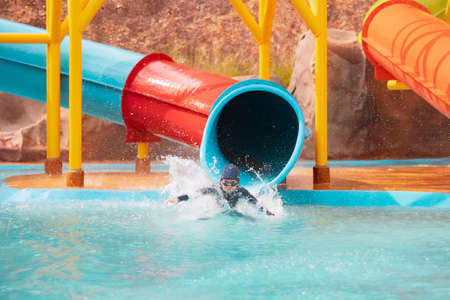 Asian child girl having fun to slide down on water slide in a water park at the summer time.の写真素材