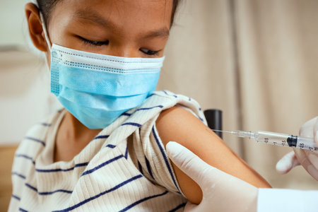Doctor injecting vaccination on asian child girl arm. The child girl wearing protection face mask...