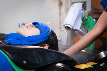 Young asian woman getting a hair wash and spa treatment by hairdresser at hair salon. Hairdresser doing treatment and spa hair of a young woman. Beauty salon, hair care and people lifestyles concept.の写真素材