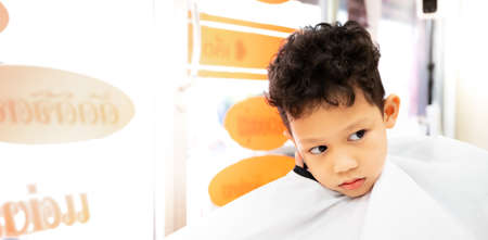Cute asian child boy getting hair cut by hairdresser at hair salon. Hair care and childhood lifestyle concept.の写真素材