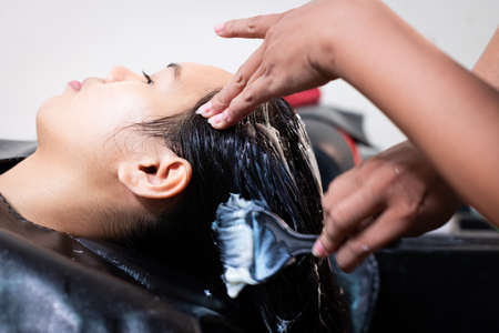 Young asian woman getting a hair wash by hairdresser at hair salon. Hairdresser washing hair of a young woman. Beauty salon, hair care and people lifestyles concept.の写真素材