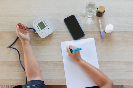 Asian young woman is checking blood pressure and heart rate with digital pressure gauge by herself...