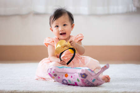 Cute asian baby girl sitting in the living room and smiling while playing with her parent.の写真素材