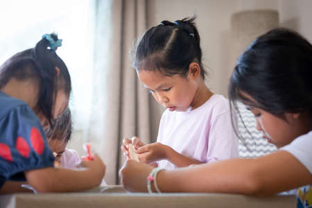 Asian child girl and friends are decorating cookies for party together with fun. DIY homemade kid art and craft concept.の写真素材