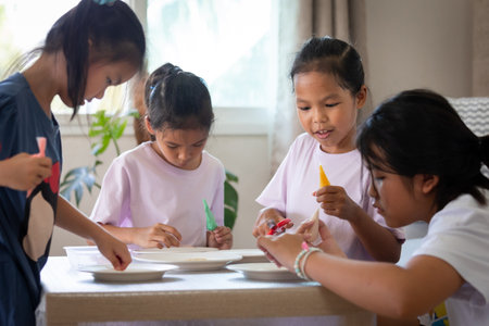 Asian child girl and friends are decorating cookies for party together with fun. DIY homemade kid art and craft concept.の写真素材