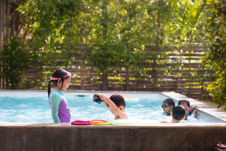 Asian children girls and boys playing water and swimming together in the swimming pool with fun....