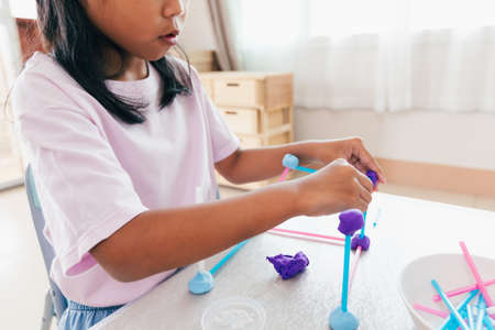 Cute asian child girl playing and creating with playdough and straws.の写真素材