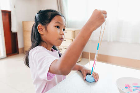 Cute asian child girl playing and creating with playdough and straws.の写真素材