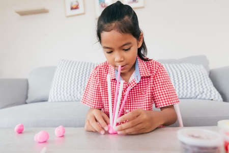 Cute asian child girl playing and creating with playdough and straws.の写真素材