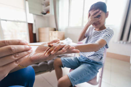 Asian child girl feeling scared while parent helping her perform first aid finger injury after she has been an accident.の写真素材
