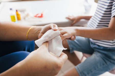 Parent helping her child perform first aid finger injury after she has been an accident.の写真素材