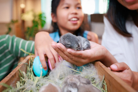 Asian mother and her daughters are playing with baby bunny and decorating easter eggs preparing for...