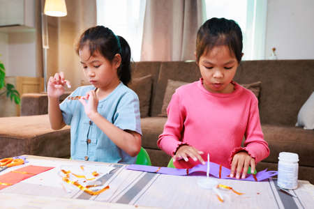 Asian siblings child girl enjoy making artwork and craft at home. Children learning online with her teacher and friend to make artwork together. Art and craft DIY for kid concept.の写真素材