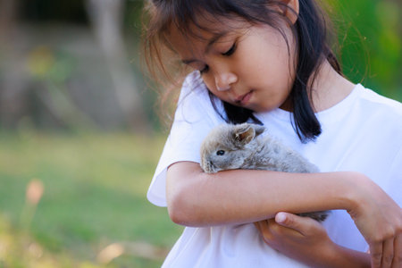 Asian girl holding adorable bunny fluffy in hand with tenderness and love. People take care and play with a pet.の写真素材
