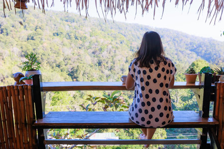 Asian woman sitting on balcony and writing idea on notebooks near fresh nature with hot drink in the morning time.の写真素材