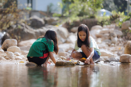 Two asian siblings playing sand nearing the river together with fun. Outdoor activity for children on vacation.の写真素材