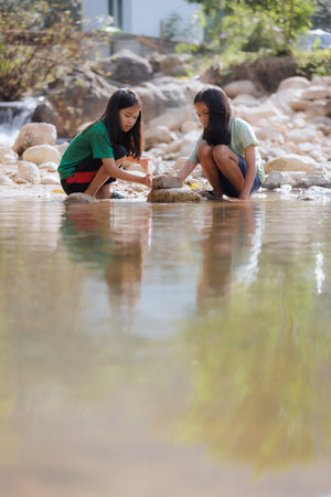 Two asian siblings playing sand nearing the river together with fun. Outdoor activity for children on vacation.の写真素材