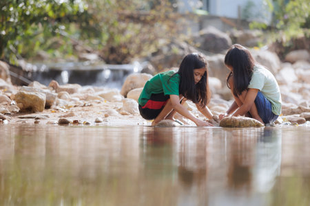 Two asian siblings playing sand nearing the river together with fun. Outdoor activity for children on vacation.の写真素材