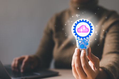 Hand holding a light bulb and there is a gear and cloud icon inside with woman using a notebook computer. Thinking imagination, Online technology, Innovation idea concept.の写真素材