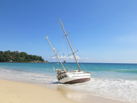 Tropical Seascape with a wooden, old and broken yellow blue boat on white beach on warm sunsetの写真素材
