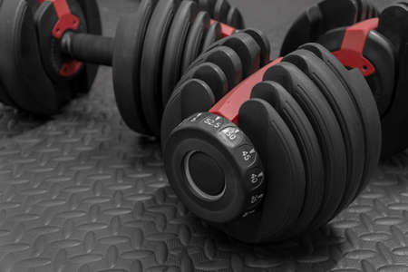 Adjustable weight dumbbell in plastic polymer material on black rubber floor.Users can choose the weight of the exercise program as needed for bodybuilding.の写真素材